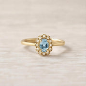 A gold ring with a blue gemstone, likely a diamond, set in the center.