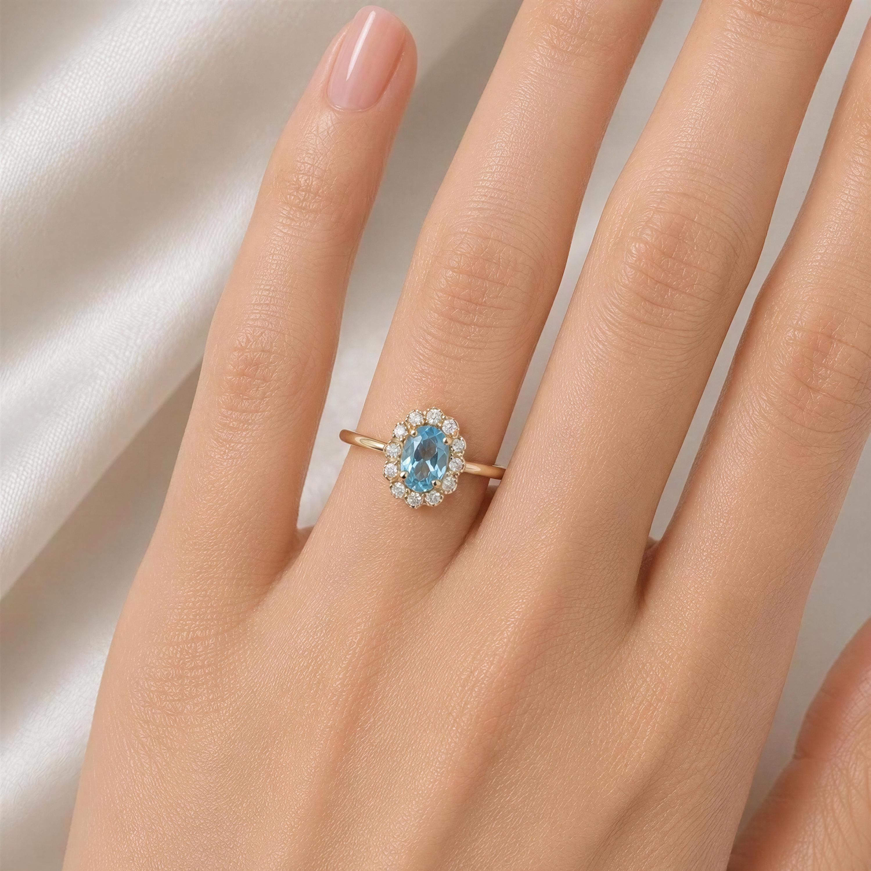 A close-up of a person's hand wearing a gold ring with a blue gemstone, specifically a blue topaz.