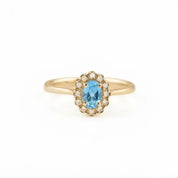 A gold ring with a large blue gemstone at the center, surrounded by smaller diamonds.