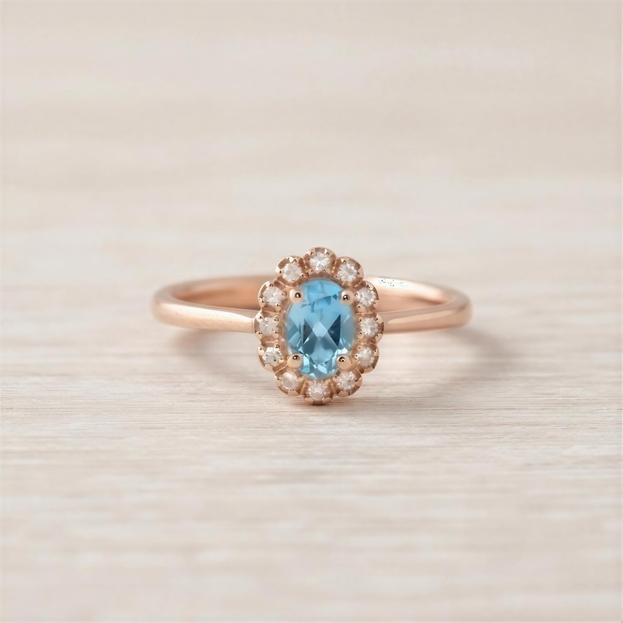 A rose gold ring with a blue gemstone set in the center, surrounded by small diamonds.