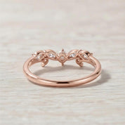 A rose gold ring with a floral design and three small stones set in the center.