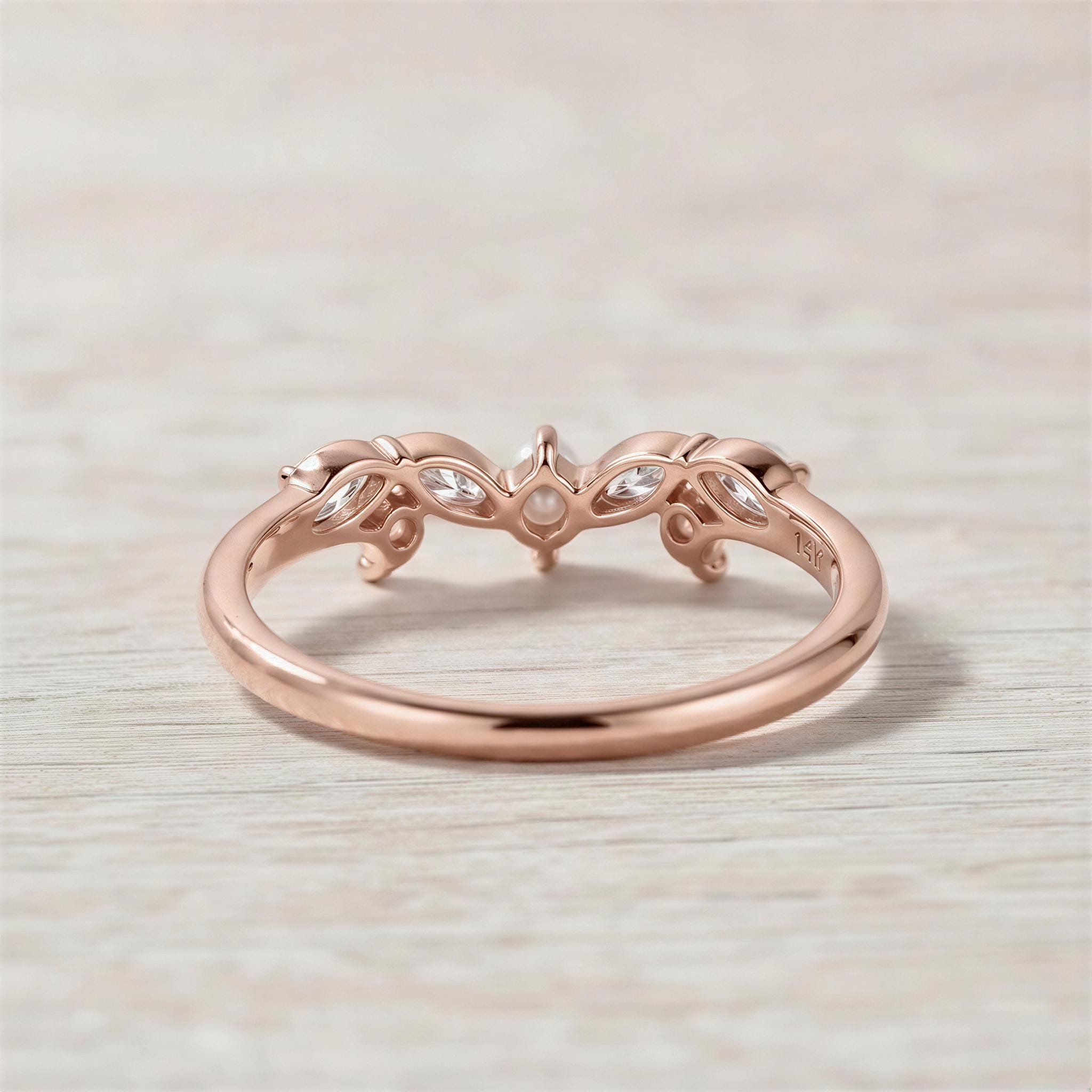 A rose gold ring with a floral design and three small stones set in the center.