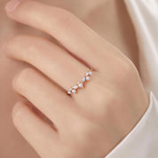 A close-up of a hand wearing a delicate gold ring with a cluster of small pearls and a small diamond.