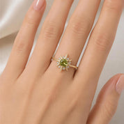 A close-up of a person's hand wearing a gold ring with a green gemstone, which appears to be a star-shaped piece.