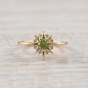 A gold ring with a large central gemstone surrounded by smaller diamonds, resembling a starburst design.
