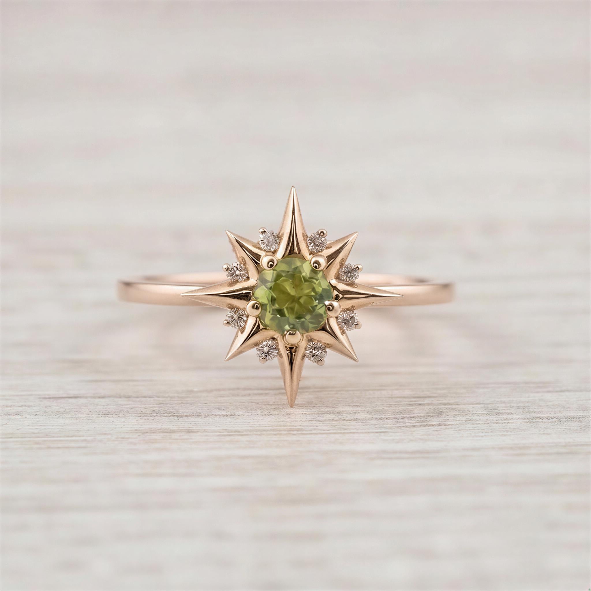 A gold ring with a large green gemstone in the center, surrounded by smaller diamonds, set against a light wooden background.
