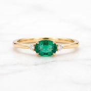 A gold ring with a large oval-shaped green gemstone in the center, surrounded by smaller diamonds.