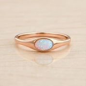A rose gold ring with a large oval opal stone set in the center.
