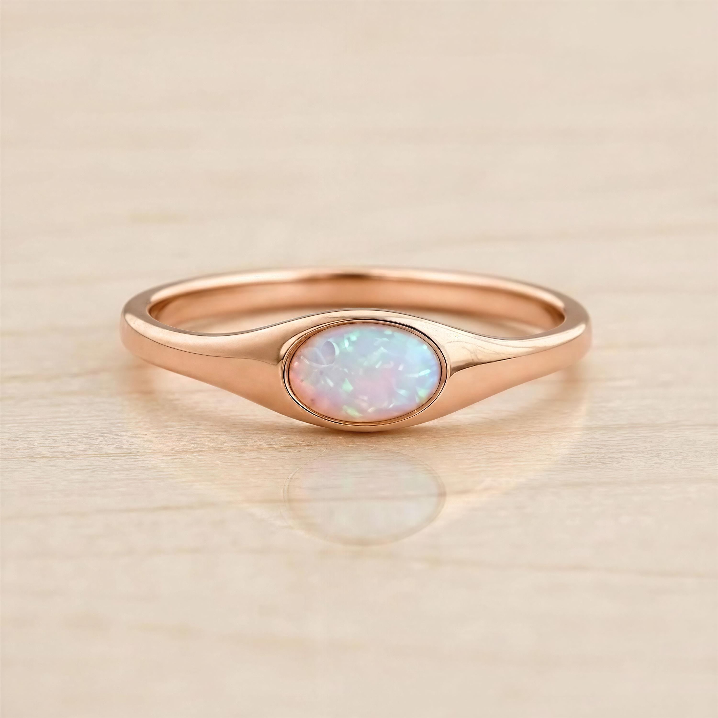 A rose gold ring with a large oval opal stone set in the center.