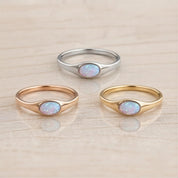Three rings with opals are displayed on a light-colored surface.