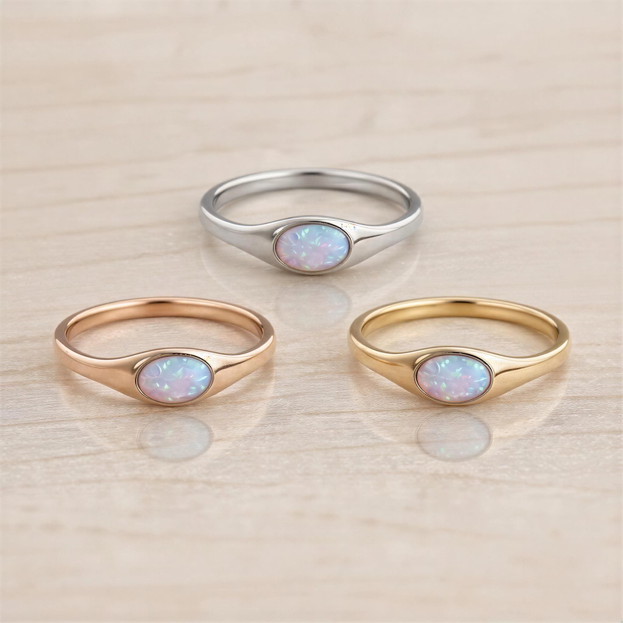 Three rings with opals are displayed on a light-colored surface.