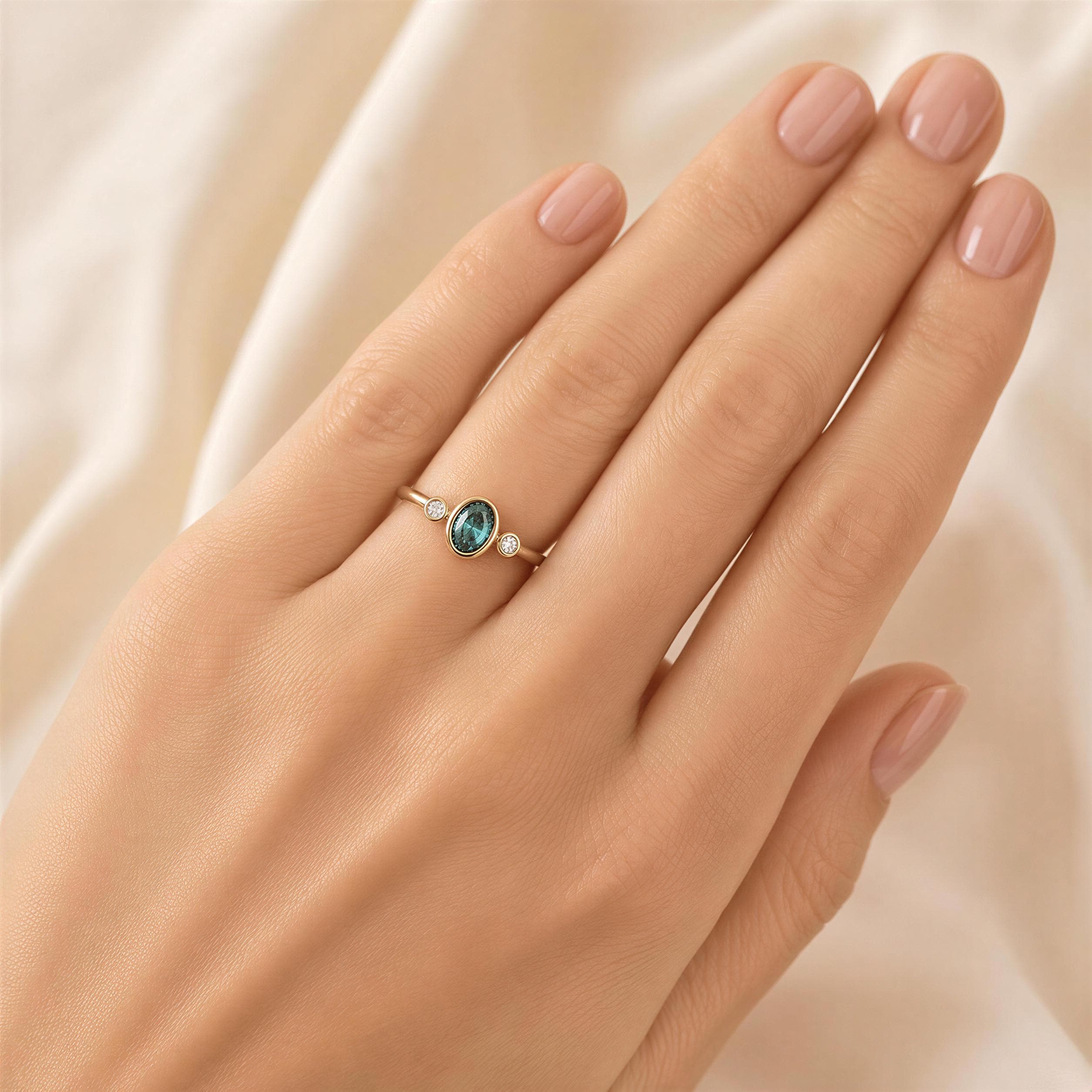 A close-up of a hand wearing a gold ring with a green gemstone.