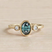A gold ring with a large oval-shaped gemstone in the center, surrounded by smaller round stones.