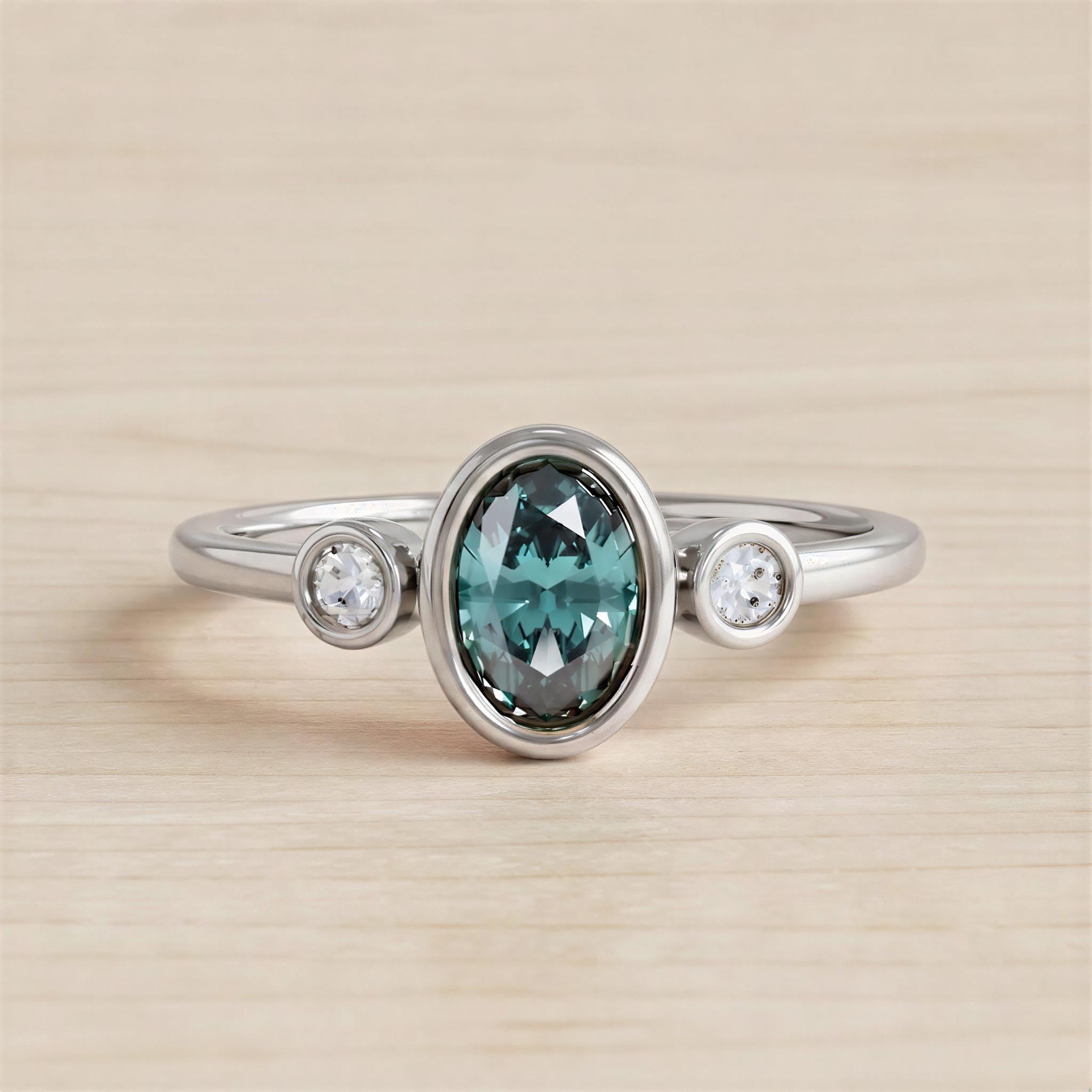 A silver ring with a large oval-shaped gemstone in the center, surrounded by smaller round stones.