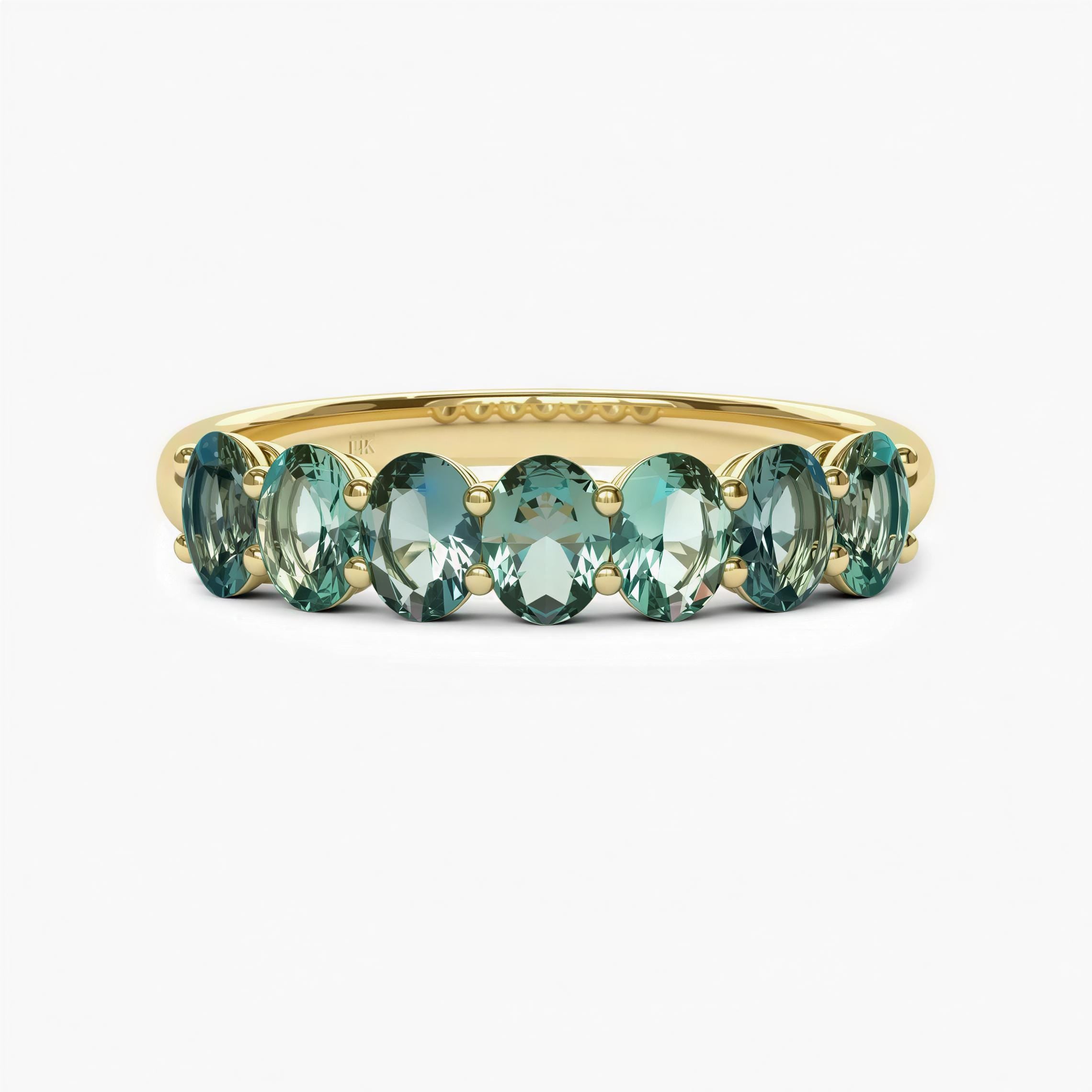 A gold ring with a row of green gemstones, likely tourmalines, set in the band.