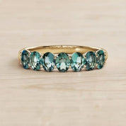 A gold ring with a row of blue sapphire gemstones set in the band.