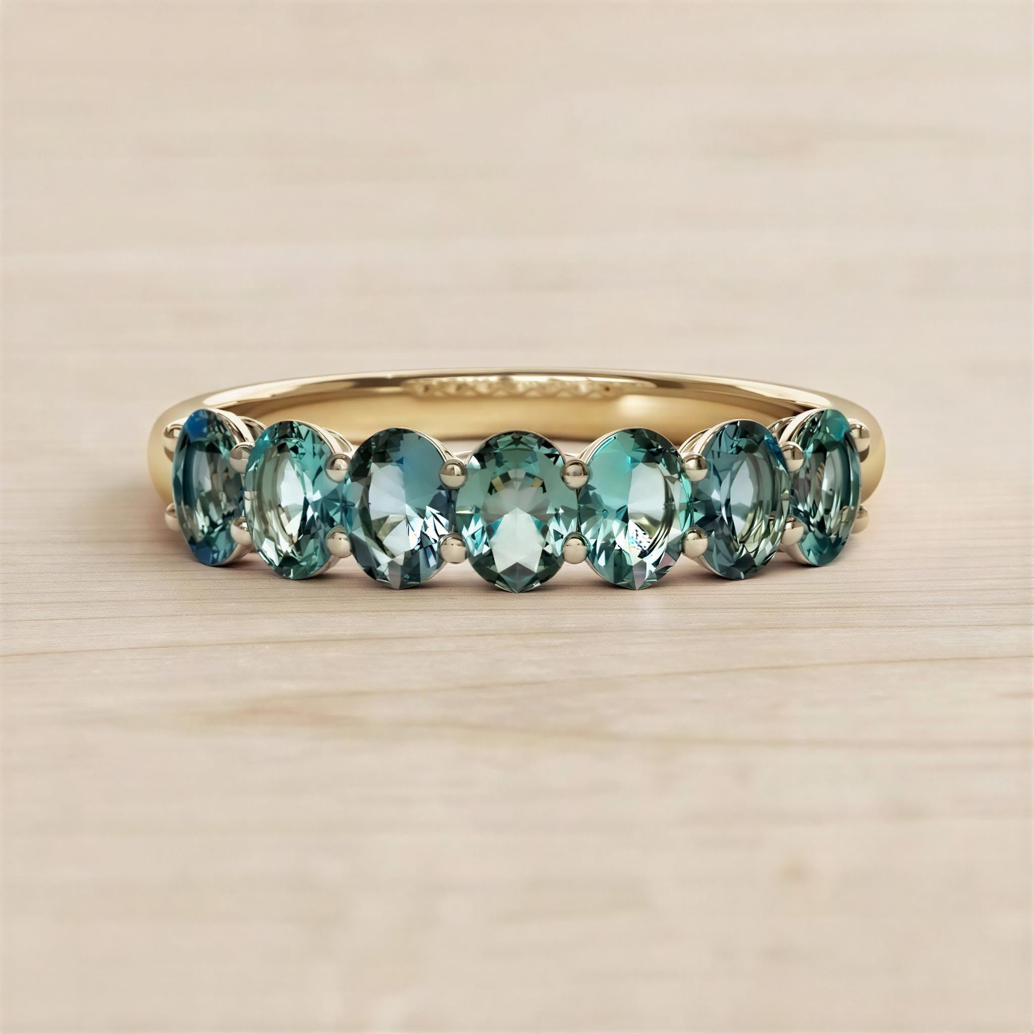 A gold ring with a row of blue sapphire gemstones set in the band.
