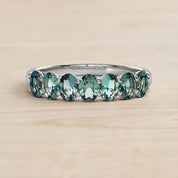 A silver ring with a row of green gemstones, likely tourmalines, set in a band.