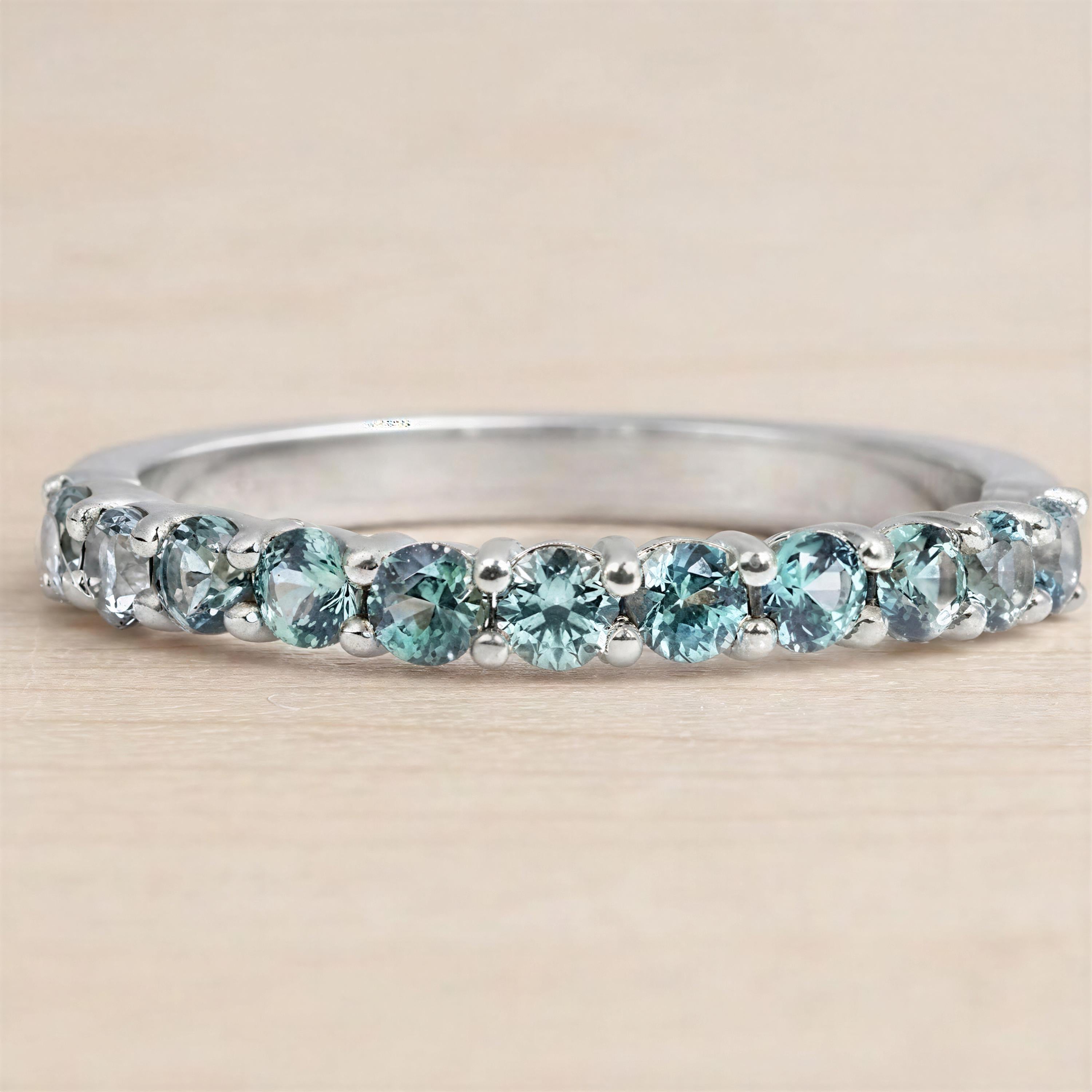 A silver ring with a row of blue gemstones, including turquoise and aquamarine stones, set in a band.
