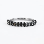 A silver ring with a row of black diamonds set in it.