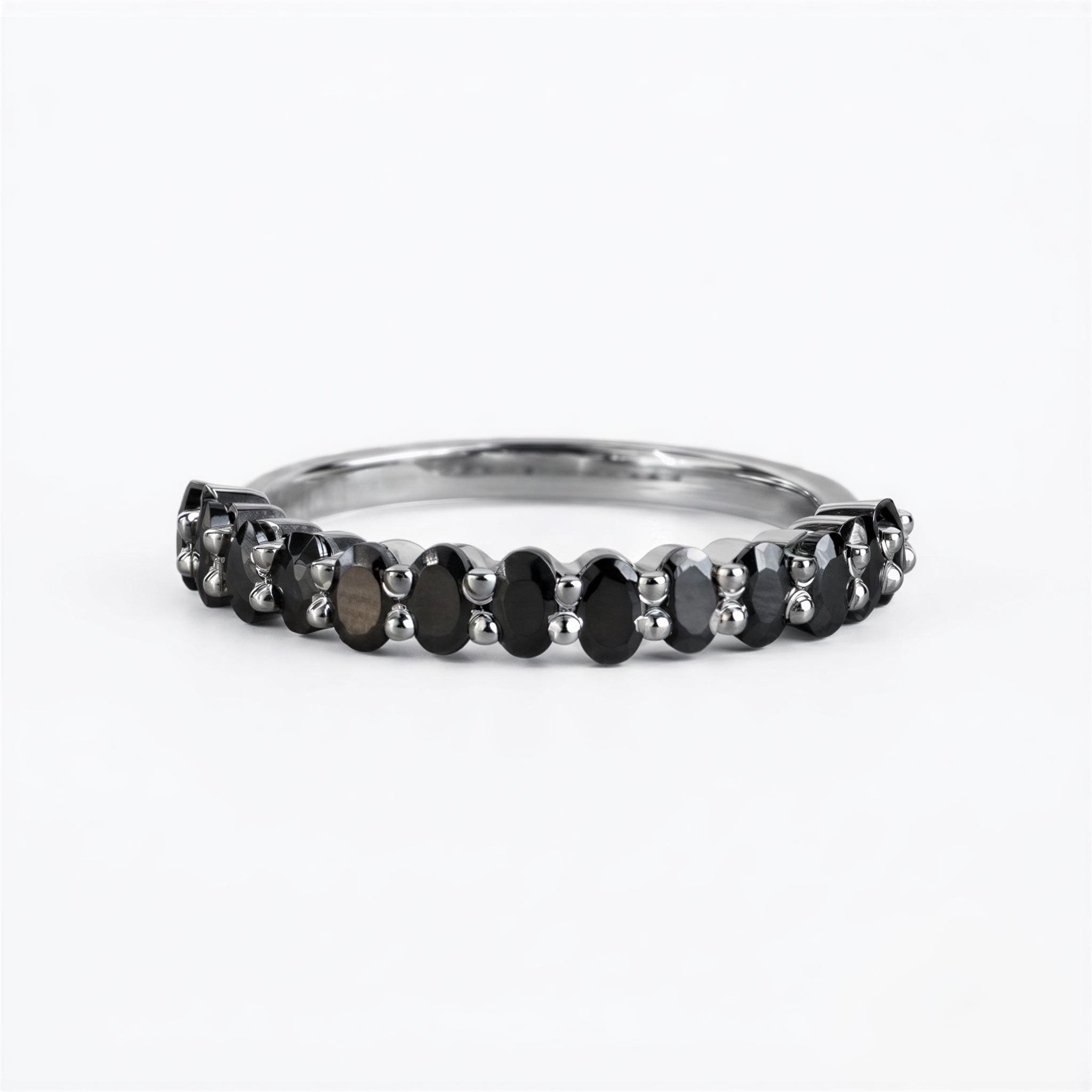 A silver ring with a row of black diamonds set in it.