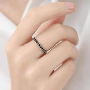 A close-up of a hand wearing a ring with black stones.
