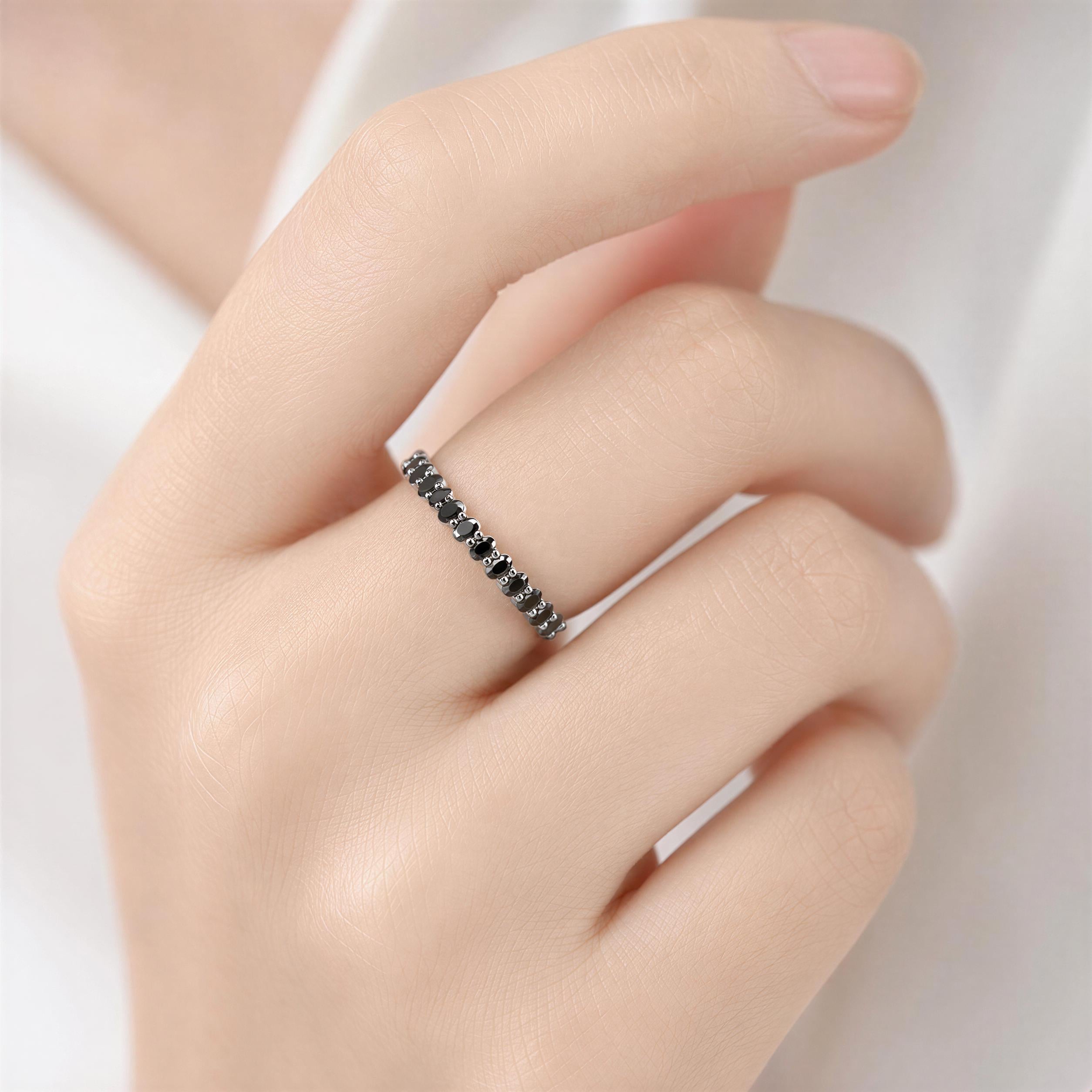 A close-up of a hand wearing a ring with black stones.
