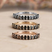 Three rings with black stones arranged in a row, each with a different color: silver, gold, and brown.