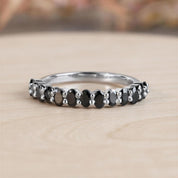 A silver ring with a row of black diamonds set in it, resting on a wooden surface.