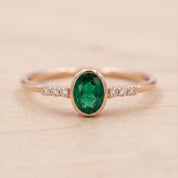A gold ring with a large oval-shaped gemstone in the center, surrounded by smaller diamonds.