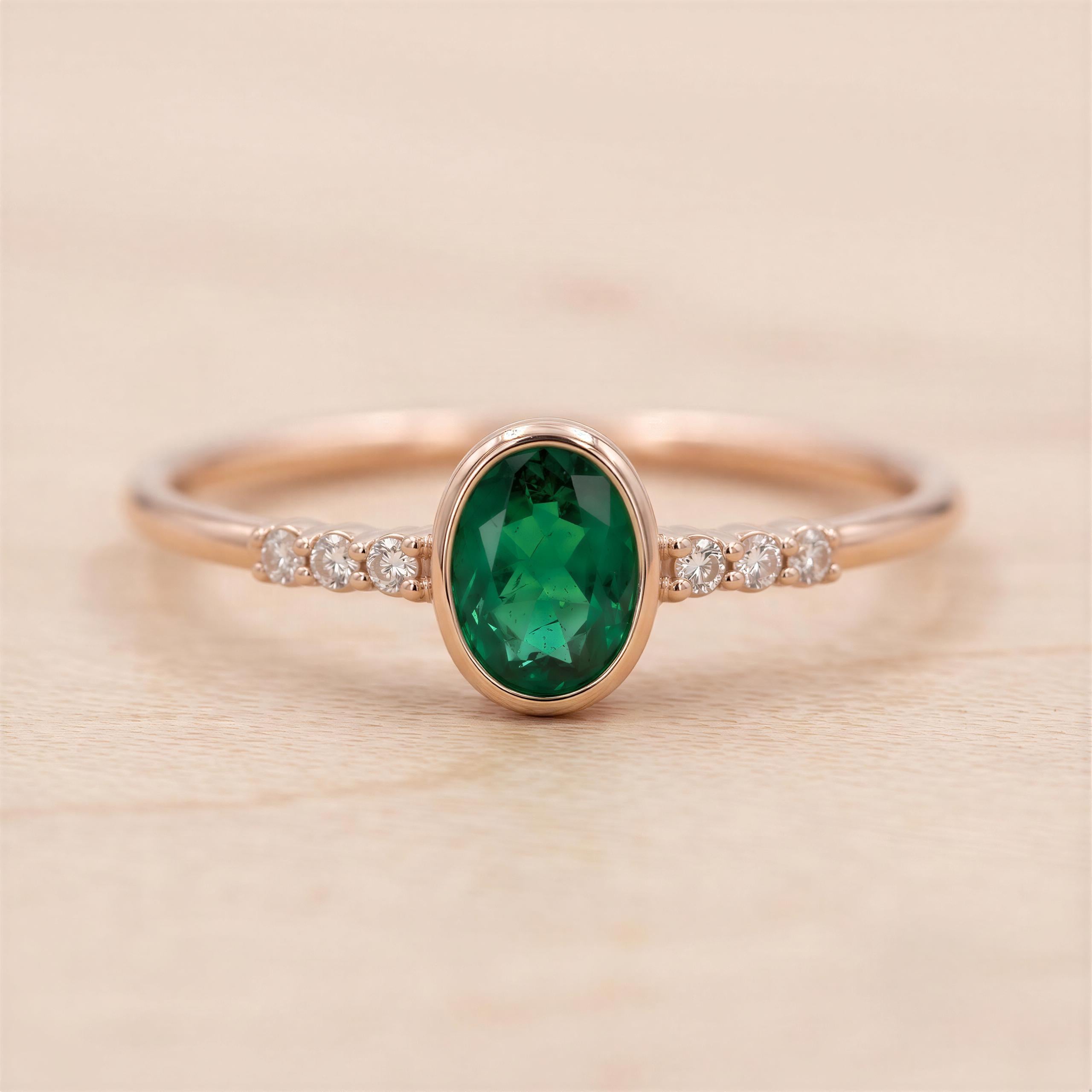 A gold ring with a large oval-shaped gemstone in the center, surrounded by smaller diamonds.