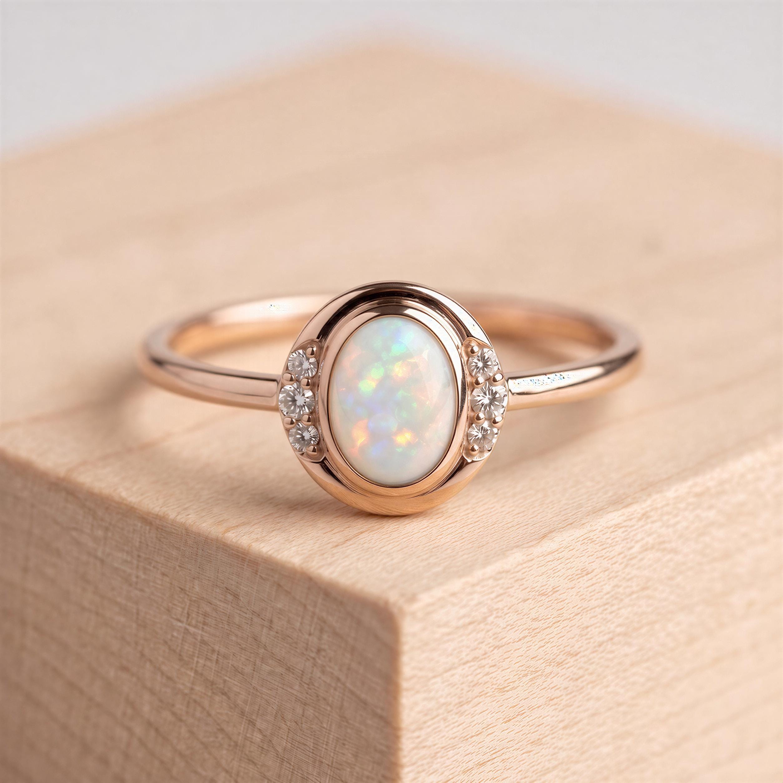 A gold ring with a large oval opal stone set in the center, surrounded by smaller diamonds.