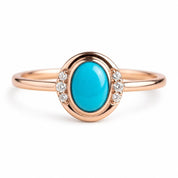 May include: A rose gold ring featuring a central oval-shaped turquoise cabochon stone. The setting is accented by three small round clear stones on each side of the turquoise, creating a symmetrical design on a smooth, polished rose gold band.
