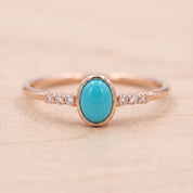 A rose gold ring with a turquoise stone and small diamonds set in the band.