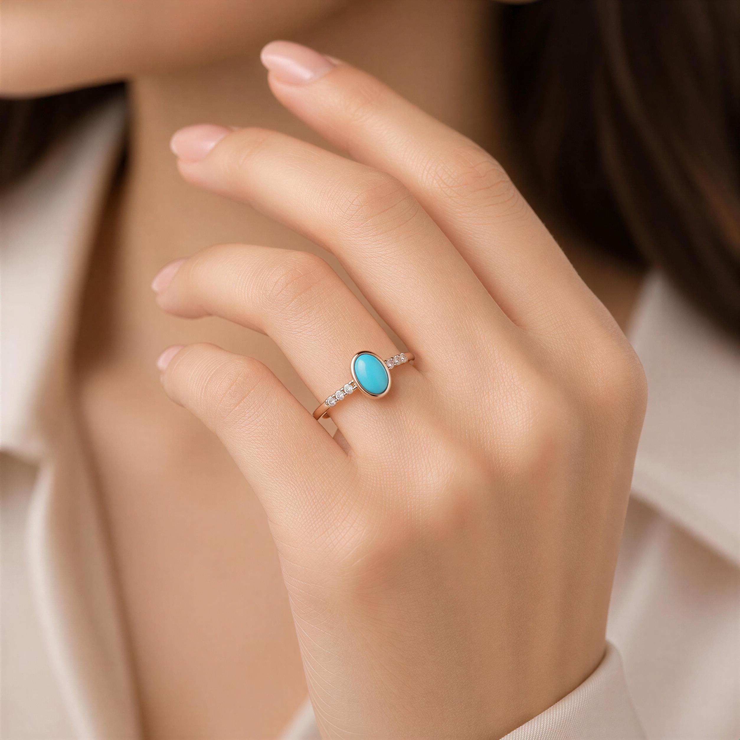 A close-up of a person's hand wearing a gold ring with a turquoise stone.