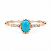 A rose gold ring with a turquoise stone and small diamonds set in the band.