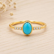 A gold ring with a turquoise stone set in the center, surrounded by small diamonds.