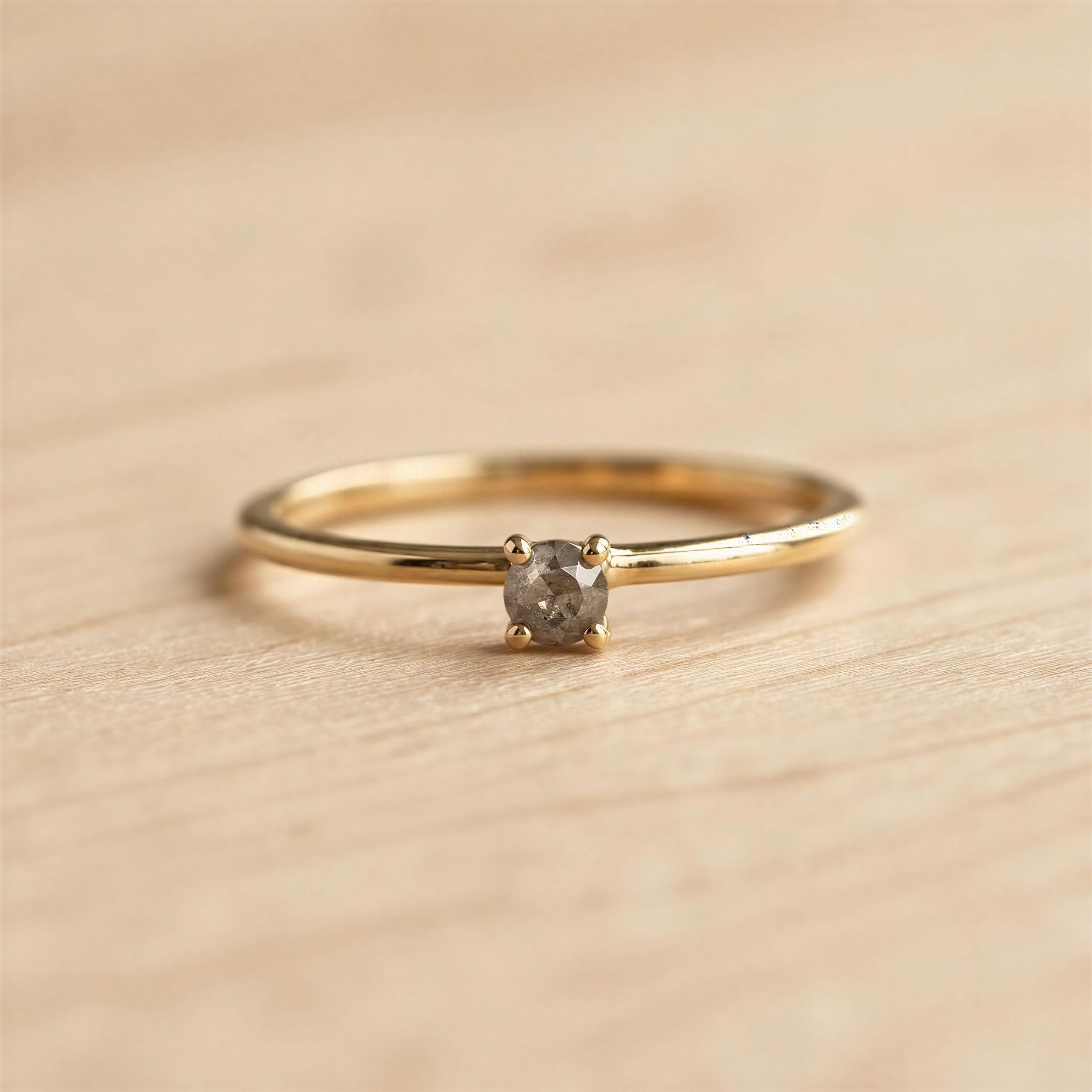 A simple gold ring with a small diamond set in the center, resting on a wooden surface.