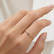 A close-up of a person's hand wearing a gold ring with a small diamond.