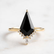A gold ring with a large black diamond as the centerpiece, surrounded by smaller diamonds.