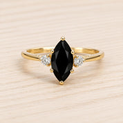 A gold ring with a large black gemstone in the center, surrounded by smaller diamonds.