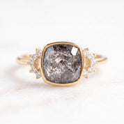 A gold ring with a large, square-cut diamond as the centerpiece, surrounded by smaller diamonds.