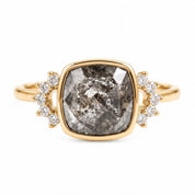 A gold ring with a large, irregularly shaped gray diamond as the centerpiece, surrounded by smaller diamonds.