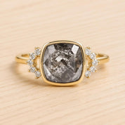 A gold ring with a large, square-cut diamond as the centerpiece, surrounded by smaller diamonds.