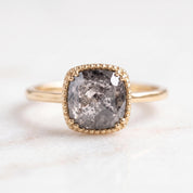 A gold ring with a large, irregularly shaped gray diamond as the centerpiece.
