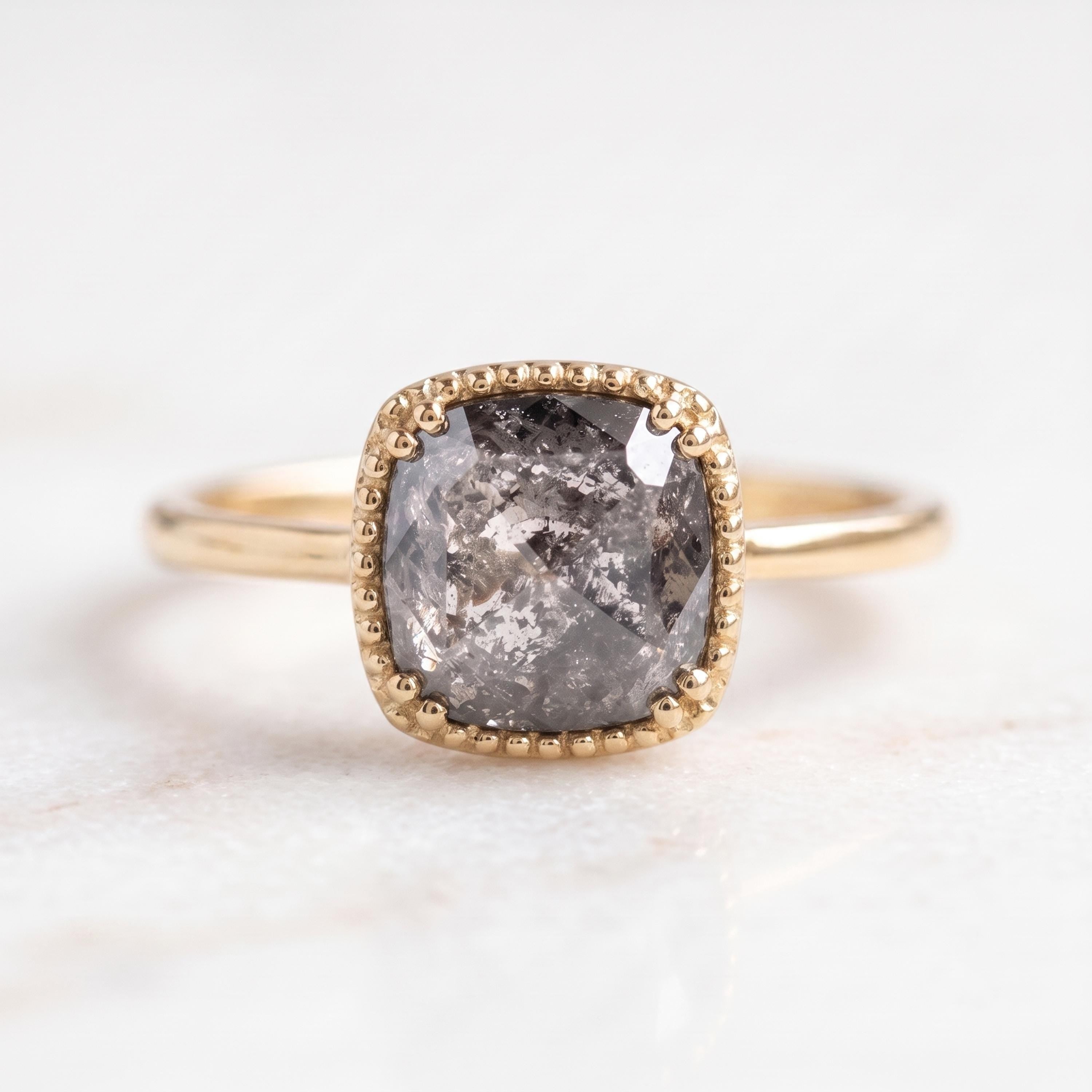 A gold ring with a large, irregularly shaped gray diamond as the centerpiece.