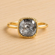 A gold ring with a large, irregularly shaped gray diamond as the centerpiece.