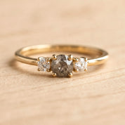 A gold ring with a large central diamond surrounded by two smaller diamonds on either side.