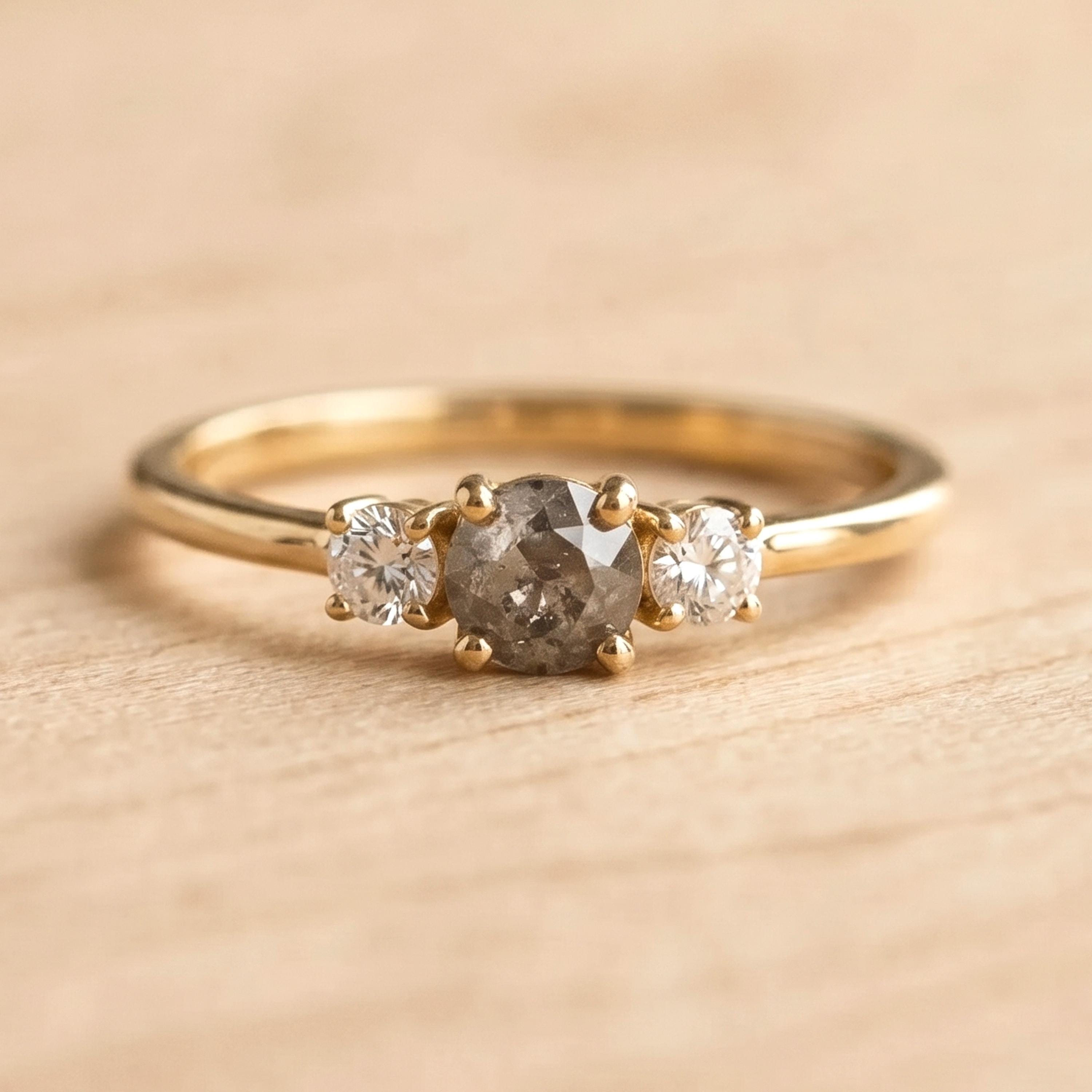 A gold ring with a large central diamond surrounded by two smaller diamonds on either side.