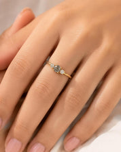 A close-up of a person's hand wearing a gold ring with a diamond and three smaller diamonds.